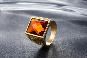 Macro detail of men's gold steel ring with square yellow gemstone and retro engraving