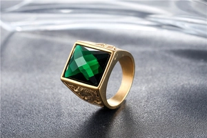 Macro shot of men's gold titanium ring with square green gemstone and vintage carvings