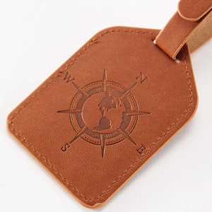 Brown PU leather luggage tag with embossed compass and earth design on white background
