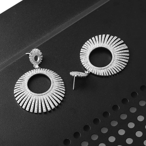 Detailed close-up of silver tassel earrings with micro-set zircons on black background