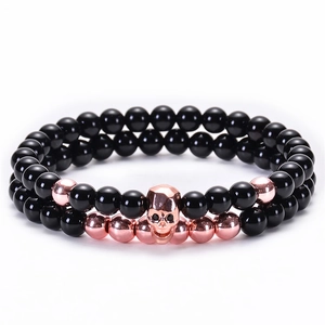 Dettaglio del bracciale a due strati in onice nera con teschio in oro rosa e perle in metallo