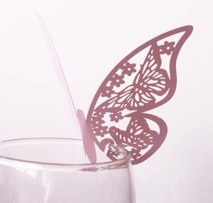Close-up of pink laser-cut hollow butterfly card used as a wedding glass decoration