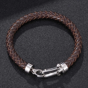 Detail of brown braided leather bracelet with silver horseshoe buckle on black texture