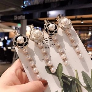 Close-up of camellia flower hair clips with pearls on a golden metal base