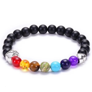 Detail eines Sieben-Chakra-Armbands mit silbernen Pfoten- und Herzanhängern auf weißem Grund