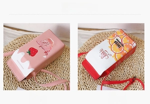 Detail view of strawberry and orange juice box shaped crossbody bags with straps