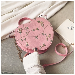Detail view of heart-shaped crossbody bag featuring floral embroidery and pink leather