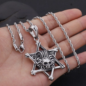 Collier avec pendentif crâne et étoile en acier inoxydable tenu sur fond de pierre sombre