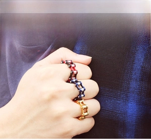 Detail of mechanical bicycle chain rings in red, blue, and gold finishes on model's hand