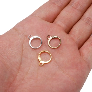 Three metal ear wire hooks in gold, silver, and bronze finish on palm for scale