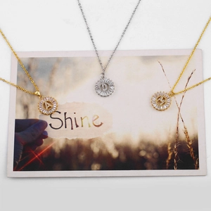Collane a girasole con lettere A, D, M in oro e argento su una cartolina Shine decorata