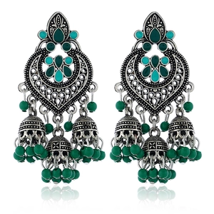 Detail of silver Jhumka earrings with green enamel beads and hollow carving design