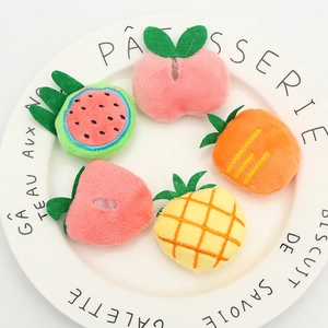 Close-up of plush watermelon, apple, and strawberry DIY accessories on a white plate