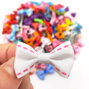 Close-up of a mini white grosgrain ribbon hair bow with pink stitched edges and metal clip