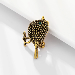 Vintage gold sparrow bird brooch with textured feathers and sparkling green gemstone eye