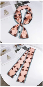 Detail of elegant pink satin twilly scarf with abstract feather print and grey-green border