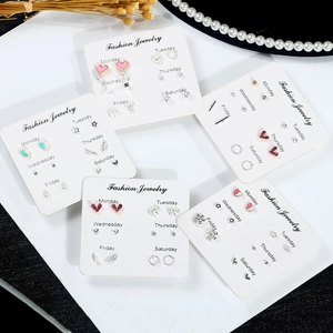 Flat lay of multiple six-pair earring sets with rhinestones and heart shapes for a week