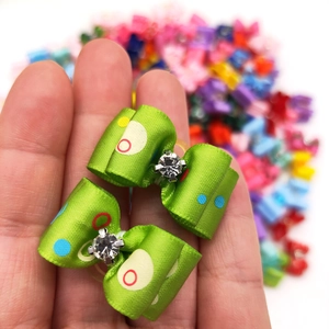 Macro view of green polka dot pet hair bows with rhinestones held in hand