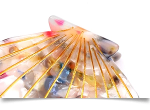 Macro view of shell-shaped acetate hair clip with marble texture and gold radial stripes