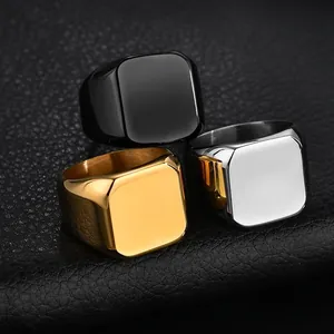 Polished stainless steel signet rings in gold, silver, and black on a textured surface