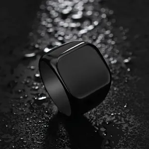 Macro shot of polished black stainless steel square ring on a dark textured water surface