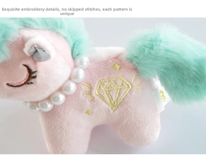 Detail of pink plush unicorn with mint green mane, pearl necklace and diamond embroidery