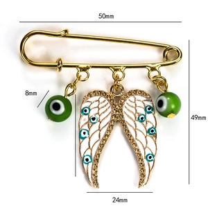 Detailed technical drawing of golden angel wing brooch with green evil eye charms