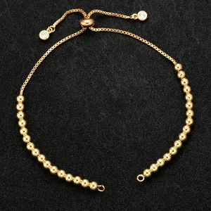 Detail of adjustable gold bead box chain with a crystal slider buckle on black surface