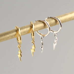 Dettaglio di due paia di orecchini a cerchio a forma di fulmine in oro e argento