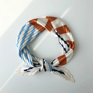 Detailed view of pleated silk scarf with blue, white, and orange geometric stripes
