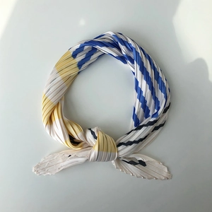 Detail of pleated silk scarf showing striped geometric patterns in blue and yellow