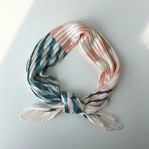 Detail view of a knotted pleated scarf featuring blue pink and beige striped patterns