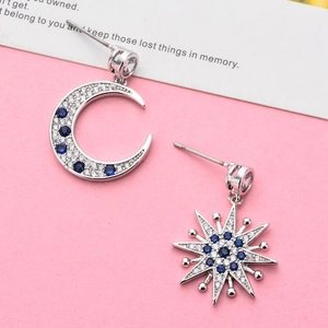 Chic asymmetric star and moon stud earrings with blue and clear zircon on pink background