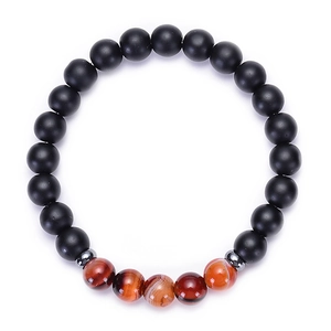 Détail macro de perles en pierre noire mate et d'agate rayée sur un bracelet élastique