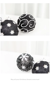 Close-up of black Christmas balls with white glitter snowflake and swirl patterns