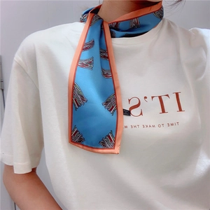 Detail of a blue geometric silk scarf tied as a stylish necktie with orange hem