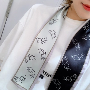 Detail of black and white silk scarf with abstract face line art worn by a model