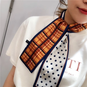 Detail of double-sided silk twilly scarf with plaid and polka dot pattern worn on neck