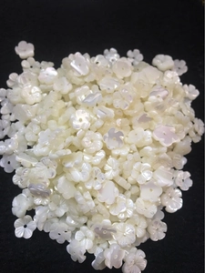 Macro shot of 10mm white shell flower beads with five petals and center holes