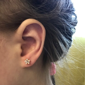 Detail of 316L stainless steel flower stud earring with cubic zirconia on ear