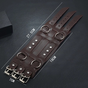 Brown leather punk cuff bracelet with studs and metal rings on black background