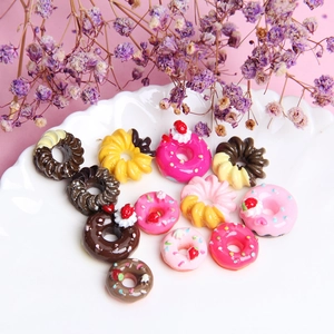 Macro shot of 14 colorful resin miniature donuts with strawberry frosting and rainbow sprinkles