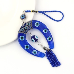 Macro view of blue evil eye horseshoe charm with hanging tassel and metal detail