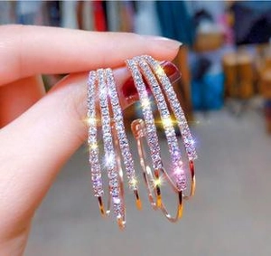 Detailed view of hand-held triple layer rose gold hoop earrings with sparkling white zircons