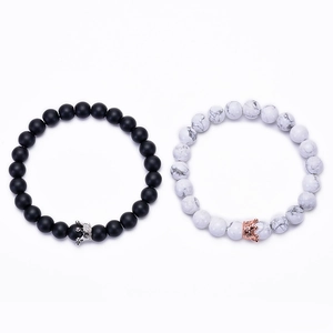 Close-up of crown couple bracelets with black matte stones and white marble beads