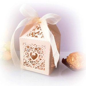 Detailed laser-cut heart pattern on a cream wedding favor box with a ribbon bow