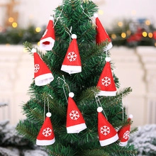 Close-up of red Christmas hat wine bottle covers with snowflakes on a festive tree