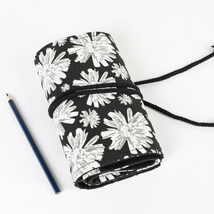 Detail of rolled black canvas pencil wrap with white daisy prints and tie closure