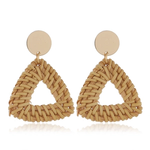 Détail de boucles d'oreilles bohèmes en rotin tressé triangle avec clous en métal doré