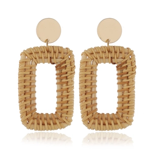 Détail de boucles d'oreilles géométriques en rotin tressé main avec clous dorés